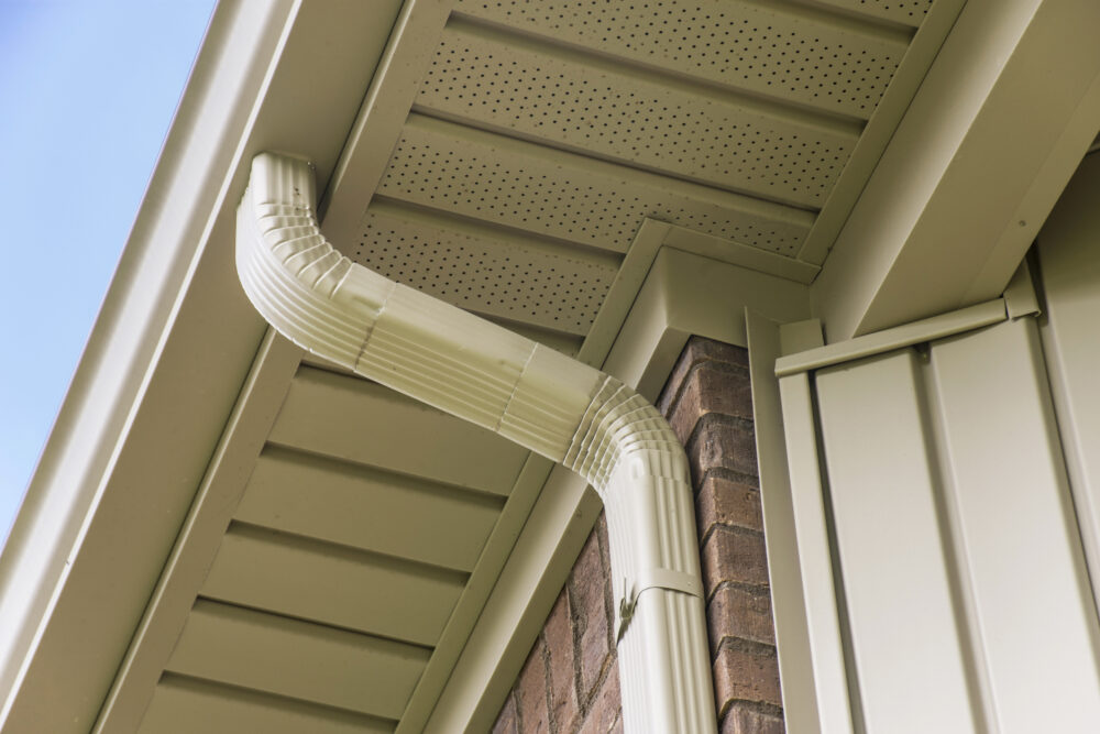 Gutter, downspout and fascia under a roof.