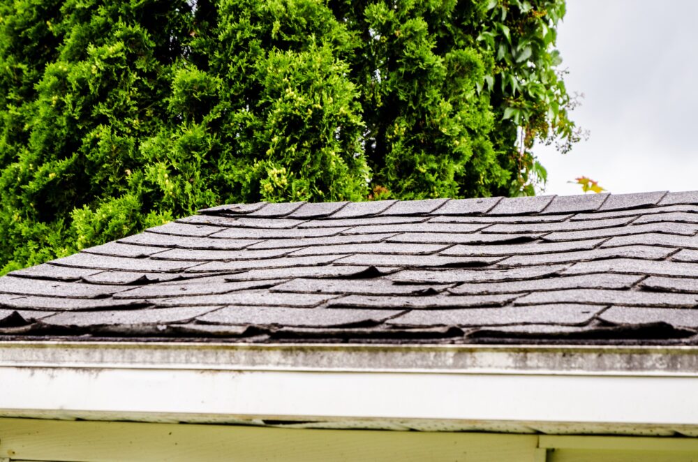 Worn and damaged roof with asphalt shingles.