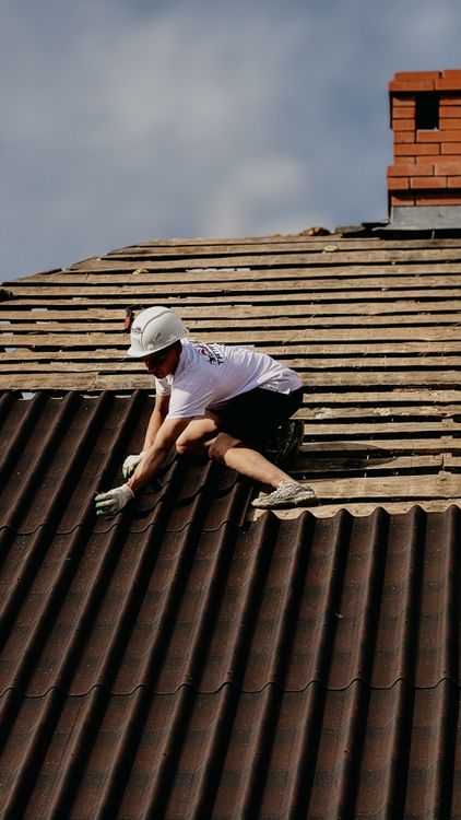 Construction worker in safety gear installing fire-resistant roofing materials